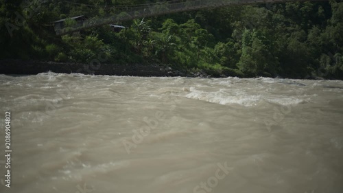 Powerful Rushing Mountain River with Traditional Himalayan Suspension Bridge in Green Forest