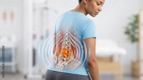 Woman experiencing lower back pain with anatomical spine illustration and radiating pain