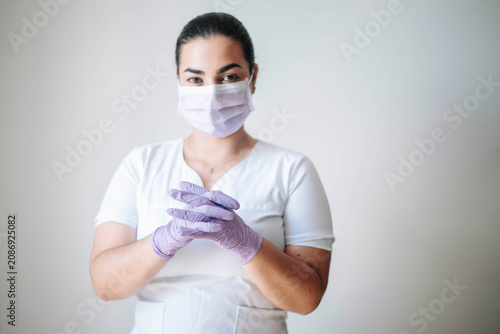 Female nurse adjusting protective gloves before assisting patients in a healthcare facility.