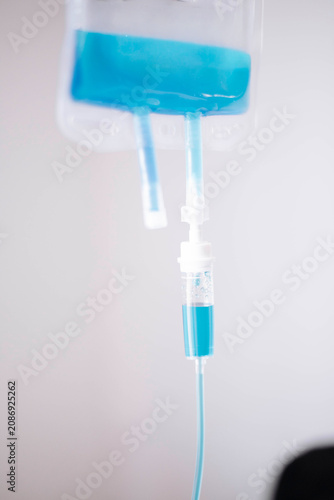 Close-up of an intravenous IV bag with blue solution prepared for patient infusion in a clinical setting.