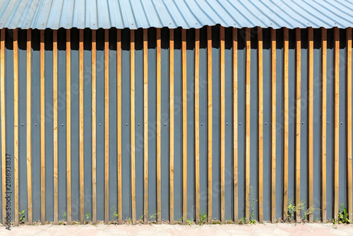 Vertical wooden slats on a corrugated metal wall.