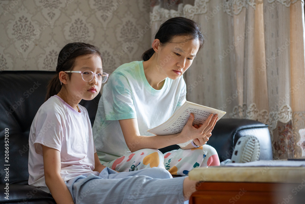 Fototapeta premium The mother helps her daughter with homework