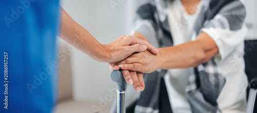 Professional caregiver offers comforting hand support to elderly