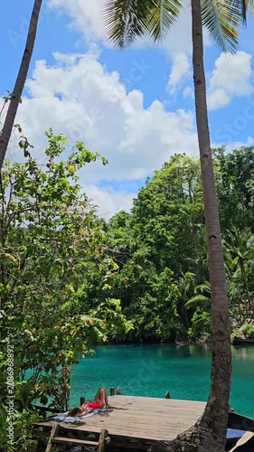 Woman sunbathing near Paisu Pok lake with blue water in Sulawesi, Banggai