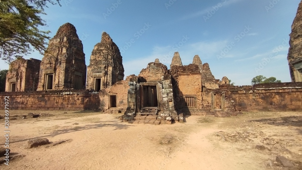 Fototapeta premium Ancient sandstone temple ruins inside Angkor Archaeological Park in Siem Reap, Cambodia. Historic Khmer architecture surrounded by tropical scenery, one of Southeast Asia's most iconic UNESCO World He