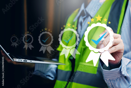 Quality assurance concept. Engineer selecting digital certification badge for construction safety compliance and workplace performance