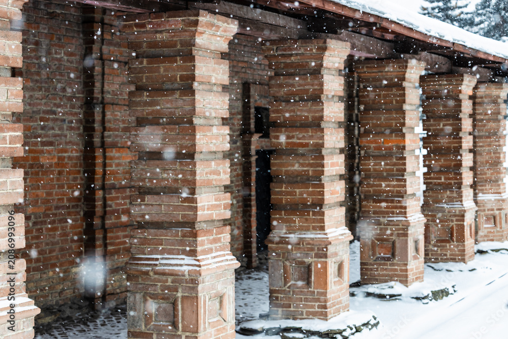 Obraz premium brick colonnade of old building during snowfall