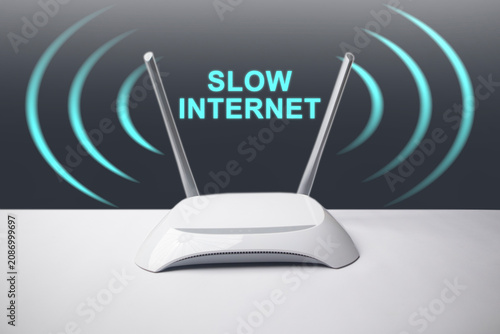 A conceptual image featuring a minimalist white wireless internet router with two antennas, surrounded by glowing blue signal waves and the overlay text SLOW INTERNET.