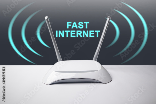 A conceptual image featuring a minimalist white wireless internet router with two antennas, surrounded by glowing blue signal waves and the overlay text FAST INTERNET.