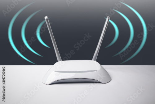 A minimalist white wireless internet router with two antennas emitting conceptual blue signal waves, set against a gradient grey background.