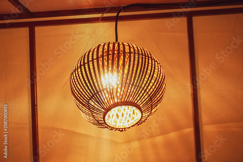 Warm Rattan Pendant Lamp Hanging Lantern Over Wooden Ceiling Creating Cozy Ambient Light