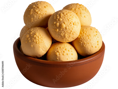 A pile of small round golden cheese bread snacks served in a rustic brown clay bowl isolated on white