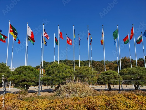 International National Flags Waving on Poles Against Blue Sky