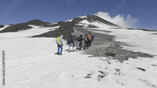 Adventurers hiking toward volcanic crater on Mount Etna in Sicily