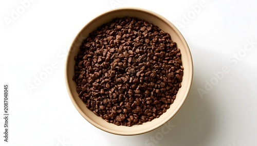 Top view of a bowl filled with roasted coffee beans on a white background.