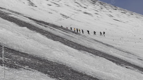 Hikers trekking across snow covered slopes of Mount Etna in Sicily