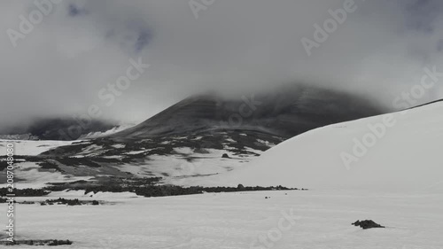 Dramatic volcanic summit of Mount Etna surrounded by moving clouds