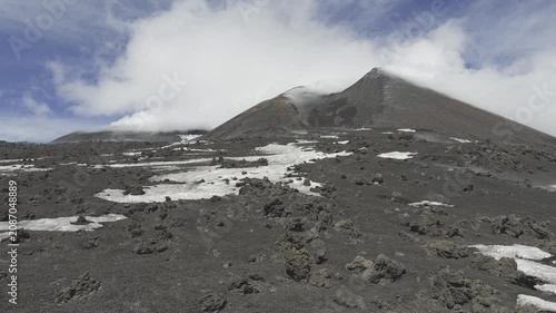 Active Mount Etna volcano rising above dark volcanic landscape in Sicily