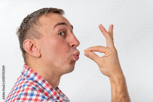Obraz na plátne Man in a casual plaid shirt is sending an air kiss with puckered lips and a hand