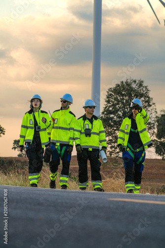 Quadro su tela The wind farm crew of four stop while the leader points out tomorrow's machines on the park road under fading skies in pink pastel dusk deep inside a tropical wind energy park image 6447