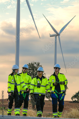 Foto The wind farm crew of four walk abreast down the centre line at dusk on the park road under fading skies in pink pastel dusk deep inside a tropical wind energy park