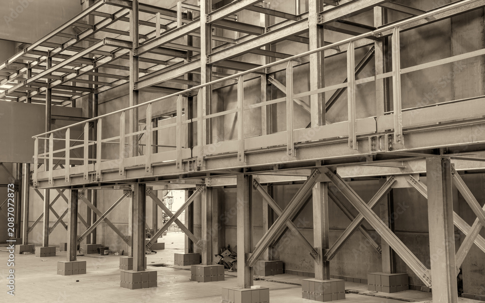 Obraz premium Large unfinished industrial space featuring metal beam framework and raw warehouse construction interior details