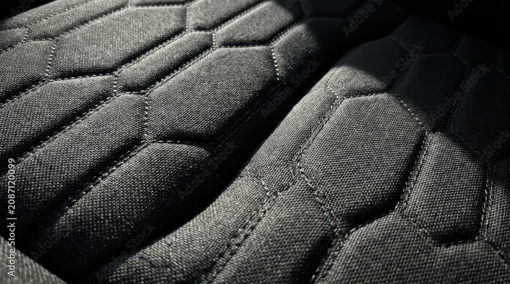 Fototapeta premium Close up view of quilted black fabric with hexagonal stitching and dramatic lighting