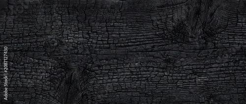 Fotografie Charred wood texture with deep cracked burned timber seamless black carbon surfa