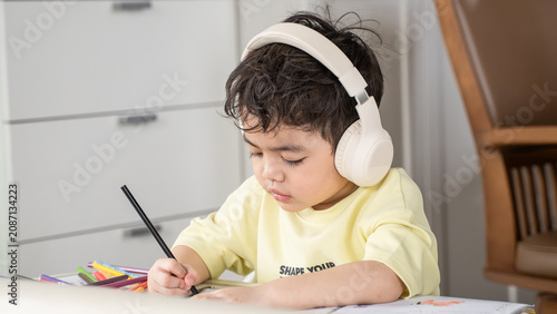 Fotografía Young boy concentrating on drawing while listening with headphones