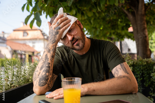 Man struggling with extreme heat in café garden during El Niño climate effect