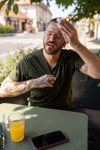 Hot weather stress, man coping with El Niño heat in café outdoor seating area