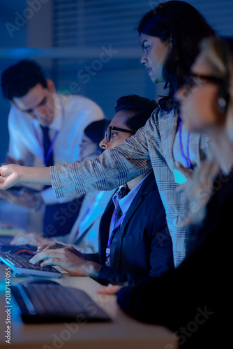 Canvastavla Operators wearing headsets work at computers in a dark modern call center monitoring data on glowing screens at night