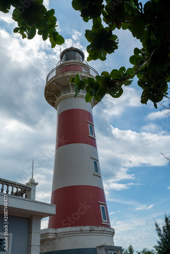 Canvas Print Ba Lang An Lighthouse on forested headland above dark basalt rocks and turquoise