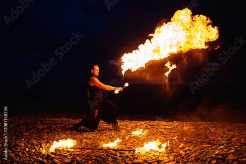 фотографія Fire breather performing with a torch on a pebble beach at night