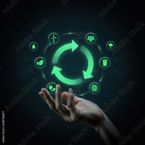 Human hand holding glowing green recycling arrows with environmental sustainability icons for green energy and eco friendly planet concept