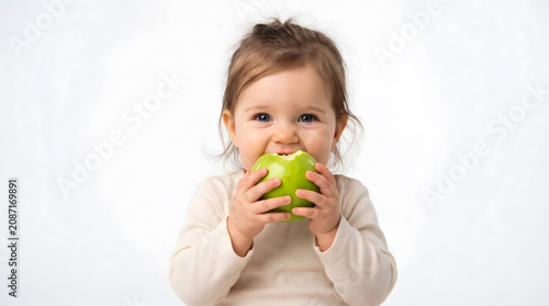 Healthy Diet, Apple Portrait, Cute baby girl eating green apple on white background Healthy food concept