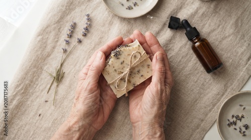 Senior hands holding handmade bar of lavender soap with essential oil