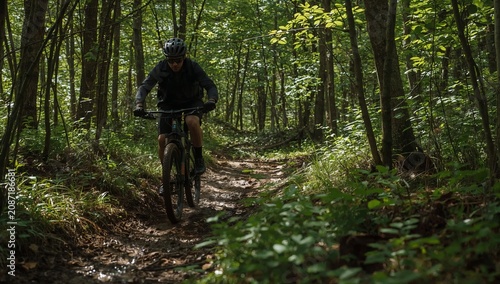 Mountain Biker Rides Along a Narrow Trail in a Dense Forest During the Day