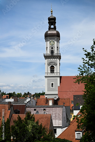 Church clock tower with onion dome above red tiled roofs