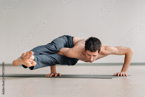 Fotografia A man with a bony torso trains lying down, doing a handstand in the gym