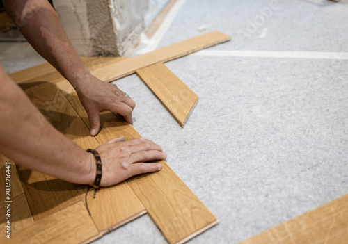 Tableau sur toile Hands aligning oak parquet planks on acoustic underlayment while creating premiu