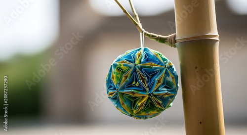Colorful modular origami kusudama ball hanging from a natural bamboo stalk