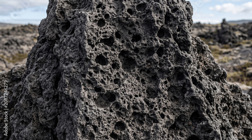 A close-up view shows a lava rock formation covered in holes