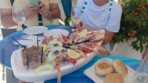 Bild auf Leinwand Pranzo di mare con plateau di crudi e calice di vino bianco