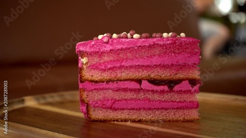 Close-up of a festive birthday cake with colorful sprinkles and lit candles spinning on a turntable.