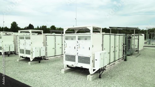 Aerial orbiting shot of a battery energy storage system facility with large containerized lithium ion units storing electricity for grid stabilization and renewable energy integration