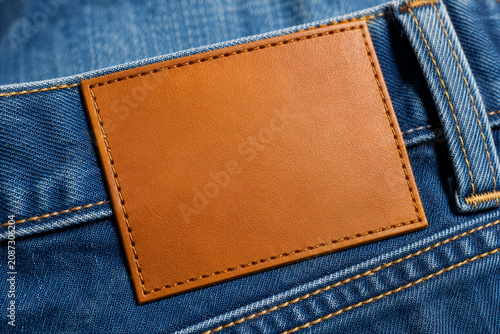 Blank brown leather patch mockup on blue denim jeans. Close up clothing label template for premium apparel branding, fashion tag design, textile branding and garment logo presentation.
