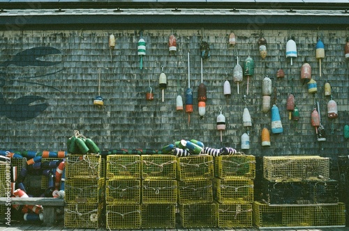 Cuadro en lienzo Colorful Lobster Traps and Fishing Buoys Against Weathered Shingle Wall at Coast