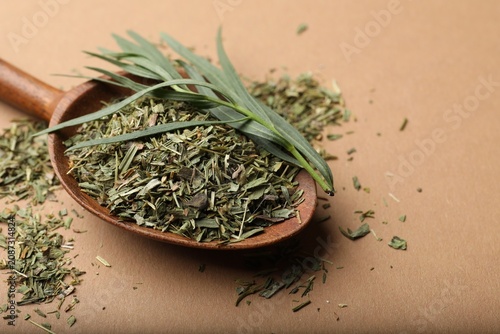 Foto Dry tarragon in spoon and fresh leaves on brown background, closeup