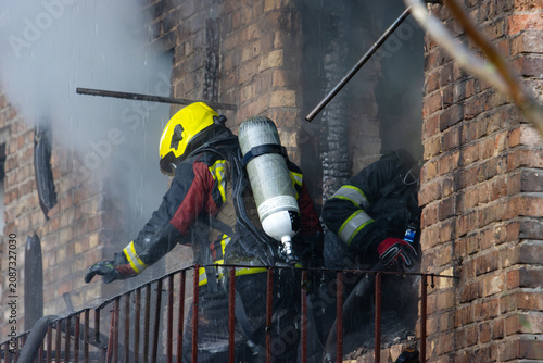 Cuadro en lienzo Two firefighters working on a heavily damaged, smoking balcony during a rescue o